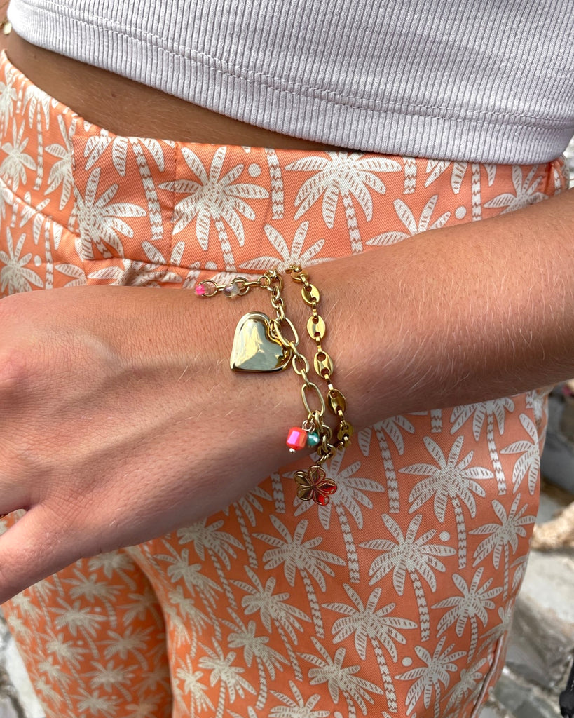 armband met bedeltjes hartje en bloem om pols.