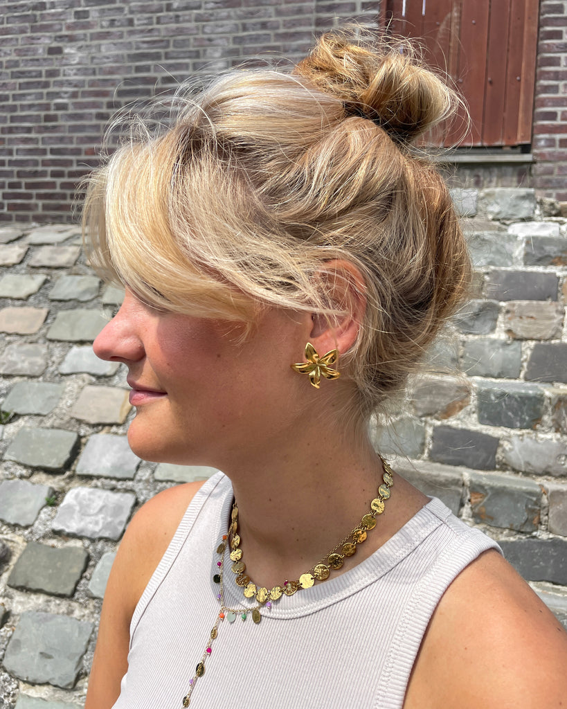 bloem oorbel in goud in oor van een vrouw.