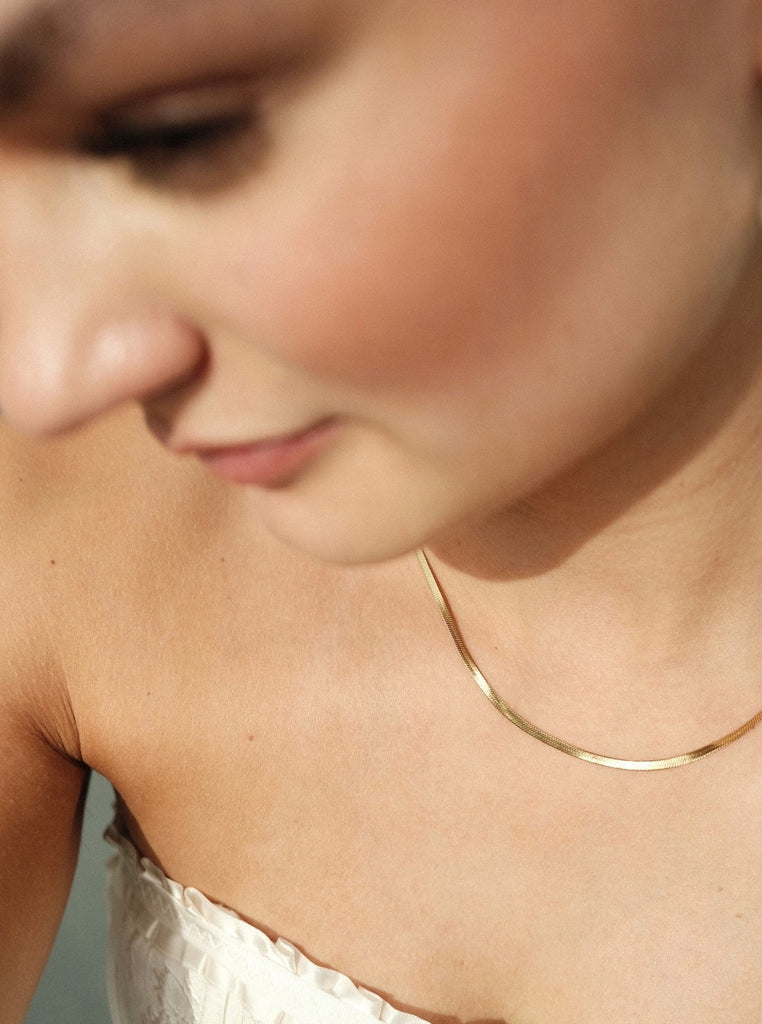 vrouw met een dunne platte gouden waterproof ketting om de hals