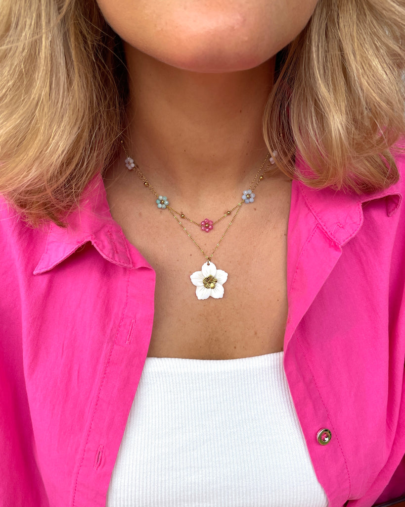 ketting met witte grote bloem bedel om hals van vrouw.