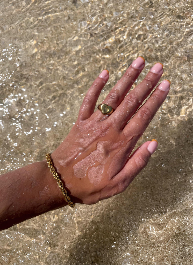 stainless steel armband om een hand en ring om een vinger boven het water